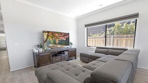 Uma sala de estar moderna com sofá seccional, televisão de tela plana e painel de entretenimento de madeira.