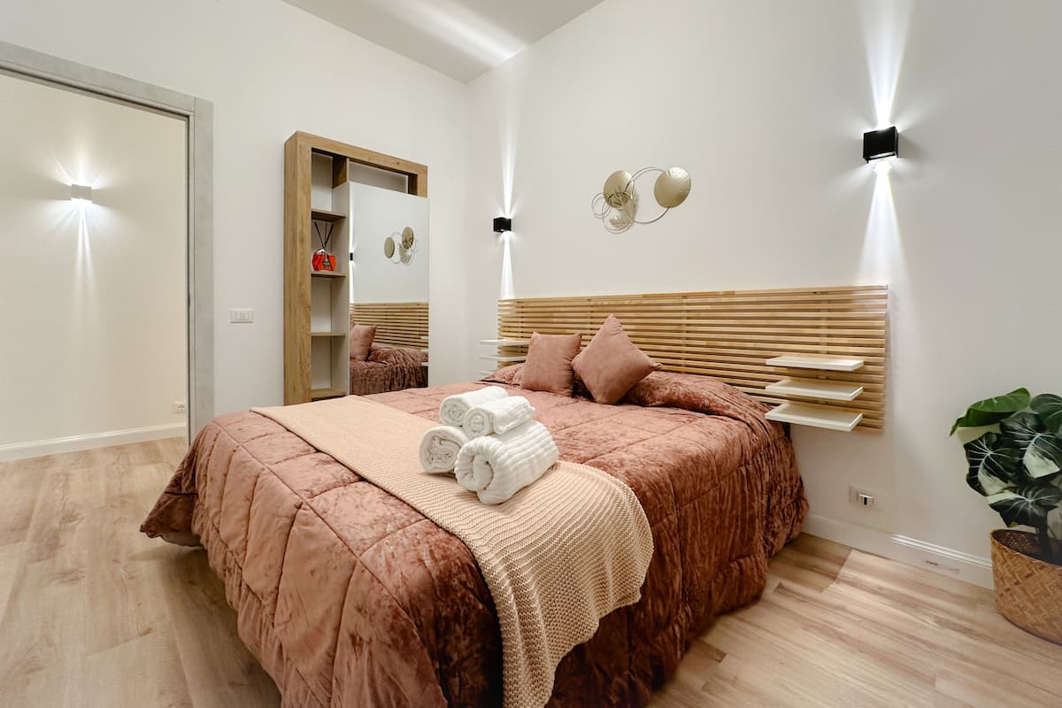 A modern bedroom with a large bed, wooden headboard, and bedside lamps.
