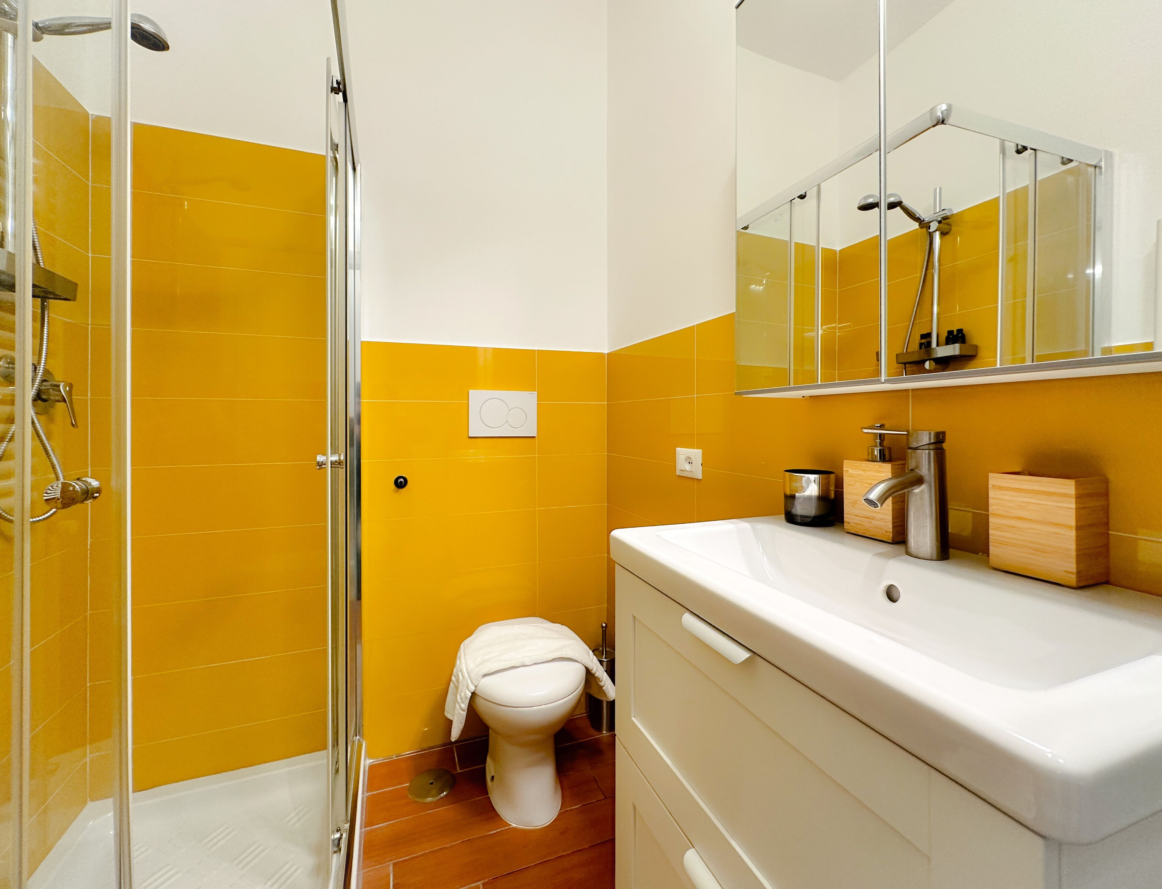 A bathroom with a glass shower enclosure, a white sink, and a mirror above the sink.