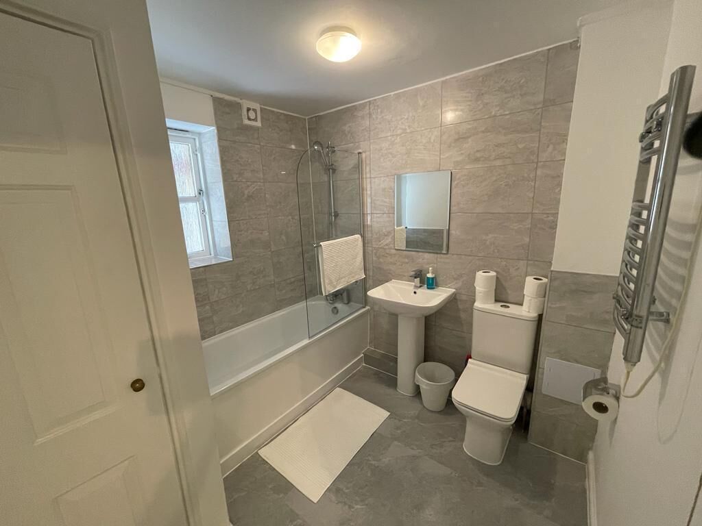 Un baño moderno con ducha, lavamanos, inodoro y espejo.