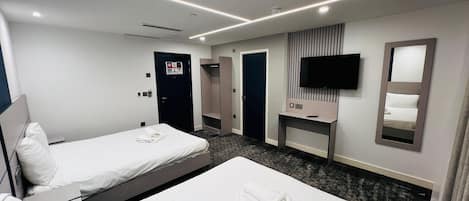 A hotel room with two beds, a TV, a mirror, and a wardrobe.