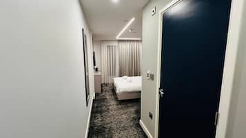 Pasillo de hotel con una cama, un escritorio y una puerta.