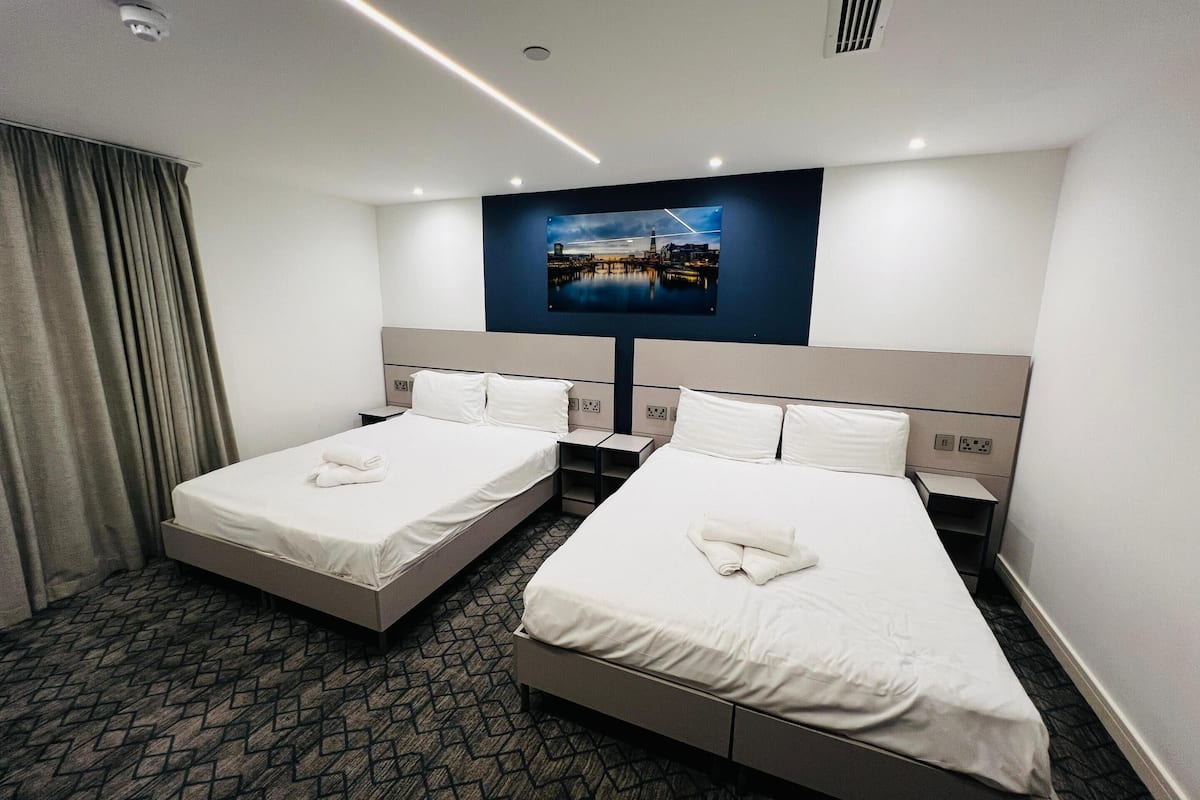 A hotel room with two beds, a large window, and a cityscape view.