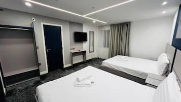 Habitación de hotel con dos camas, televisión, escritorio y armario.