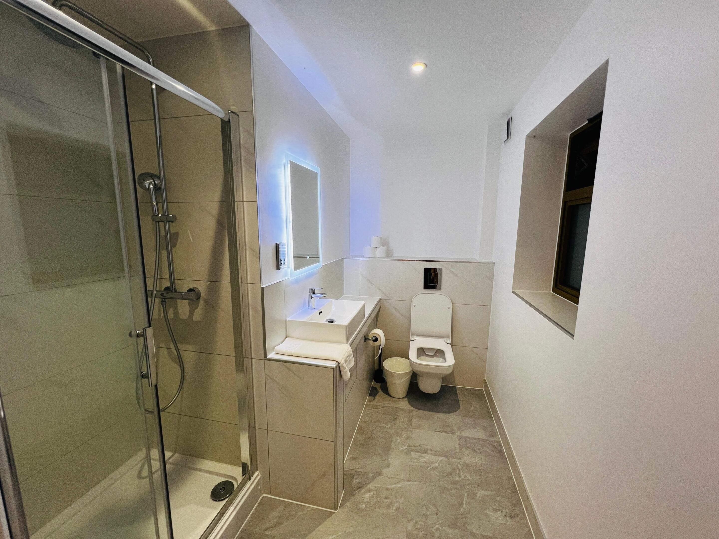 Un baño moderno con ducha de vidrio, lavamanos e inodoro.