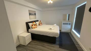 Une chambre à coucher avec un lit, une table de chevet, une commode et une fenêtre.