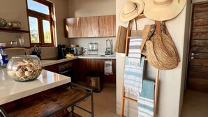A kitchen with wooden cabinets, a coffee machine, and a window with blinds.
