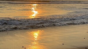 A beach with waves and a sunset.
