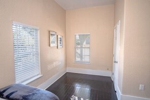 A room with two windows, a door, and a dark wooden floor.