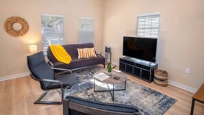 Un salon moderne avec un canapé, une table basse, un téléviseur et un ventilateur de plafond.