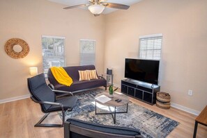 A modern living room with a sofa, a coffee table, a TV, and a ceiling fan.