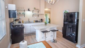 Une cuisine compacte équipée d’une cuisinière à gaz, d’un réfrigérateur et d’un coin bar avec des tabourets.