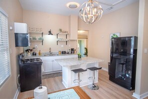 A compact kitchen with a gas stove, a refrigerator, and a bar area with stools.