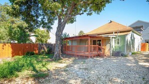 Une maison avec un porche couvert, une cour clôturée et un arbre.