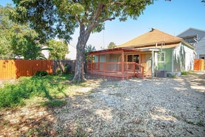 A house with a covered porch, a fenced yard, and a tree.