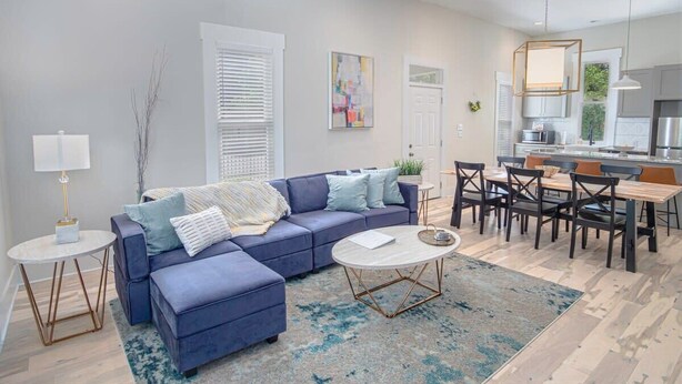 Un salon moderne avec un canapé bleu, une table basse et un coin repas comprenant une table et des chaises.