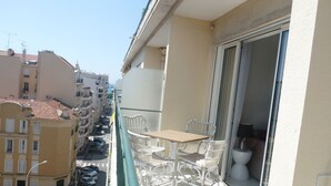Ein Balkon mit Tisch und Stühlen, Blick auf die Straße und ein Gebäude mit Balkonen.