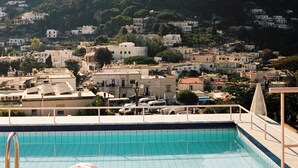 Piscina con sillas de descanso y montañas al fondo.