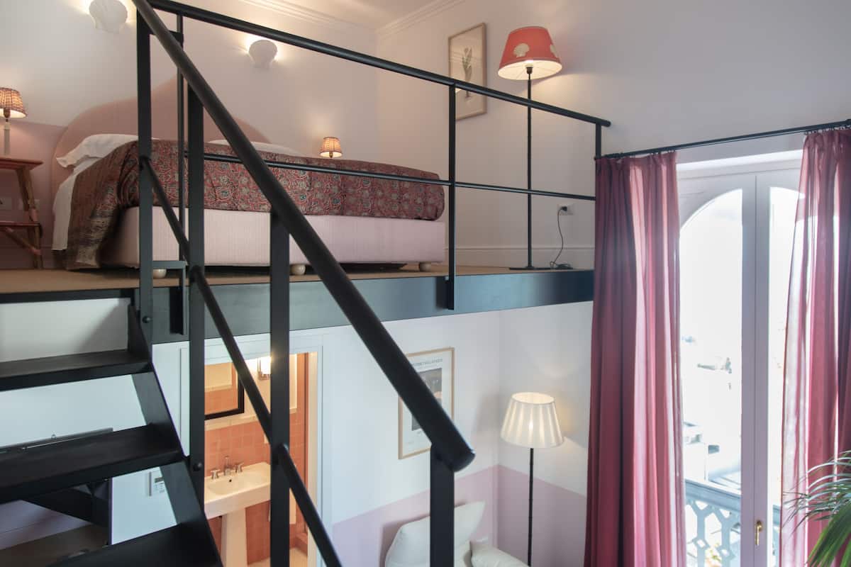 A bedroom with a bed, a nightstand, a lamp, and a window with curtains.