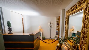 A reception desk with a potted plant, a standing lamp, and a mirror with an ornate frame. - Hotel Rhyhof (Frauenfeld)
