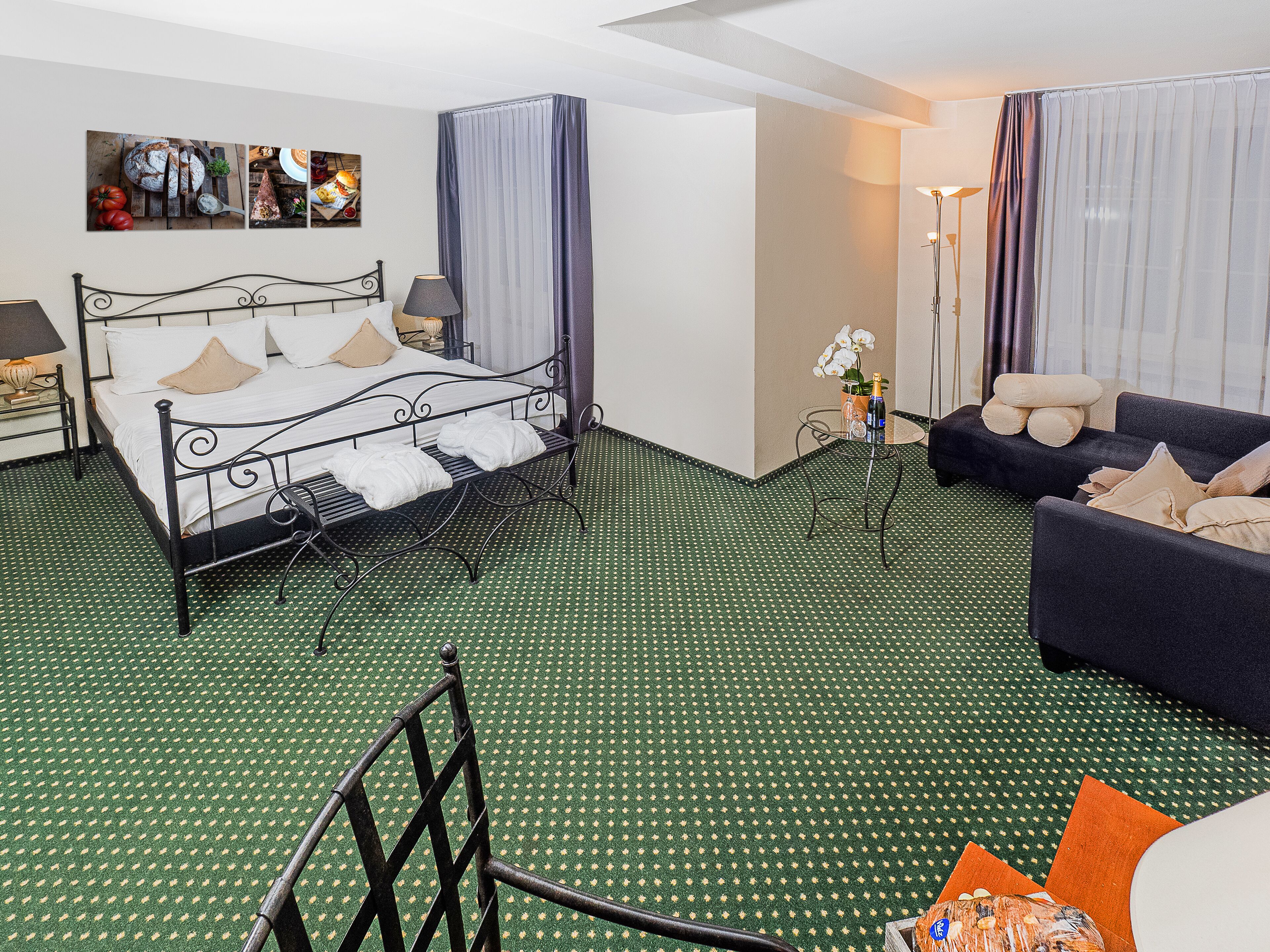 Ett hotellrum med en säng, en soffa, ett litet bord och en stol.