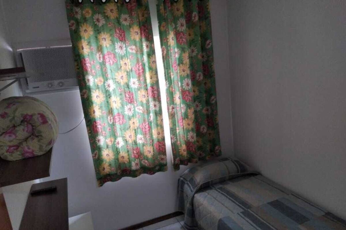 Una habitación pequeña y funcional con cama, lavadora y radiador.