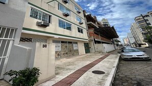A multi-story residential building with a flat facade, air conditioning units, and a gated entrance. - Pousada Louise (Balneário Camboriú)