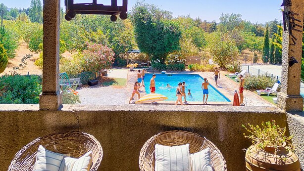 A covered outdoor area with a pool, wicker chairs, and a hanging light fixture. - Lugar da Pedra Alta (Gouveia)