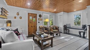 Ein gemütliches Wohnzimmer mit Holzbalkendecke, weißen Wänden und einem großen Fenster.