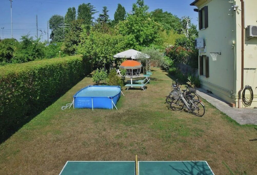 Ein Garten mit einem blauen Pool, einer überdachten Sitzgelegenheit und einem Fahrrad.