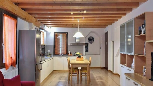 Een moderne keuken met houten balken, een eettafel en een rode bank.