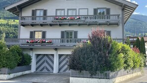 A multi-story building with balconies, a garage, and a mountainous backdrop.