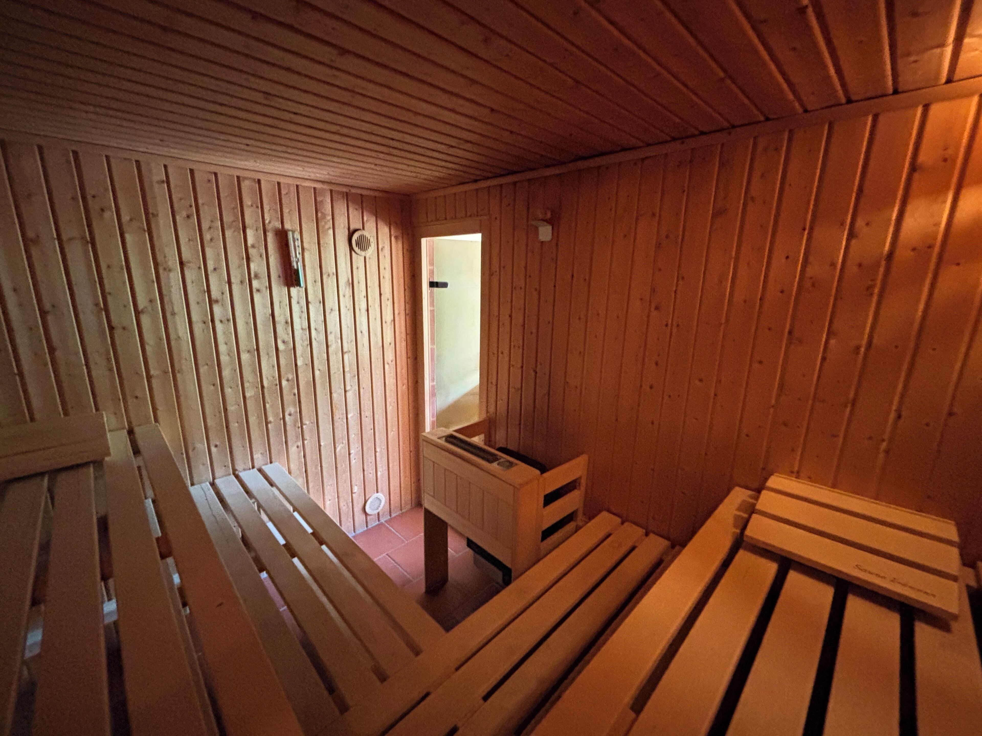 Interior de una cabaña de madera con bancos y una pequeña mesa.