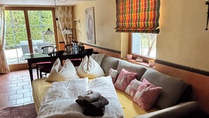 A bedroom with a bed, a sofa, a dining table, and chairs.