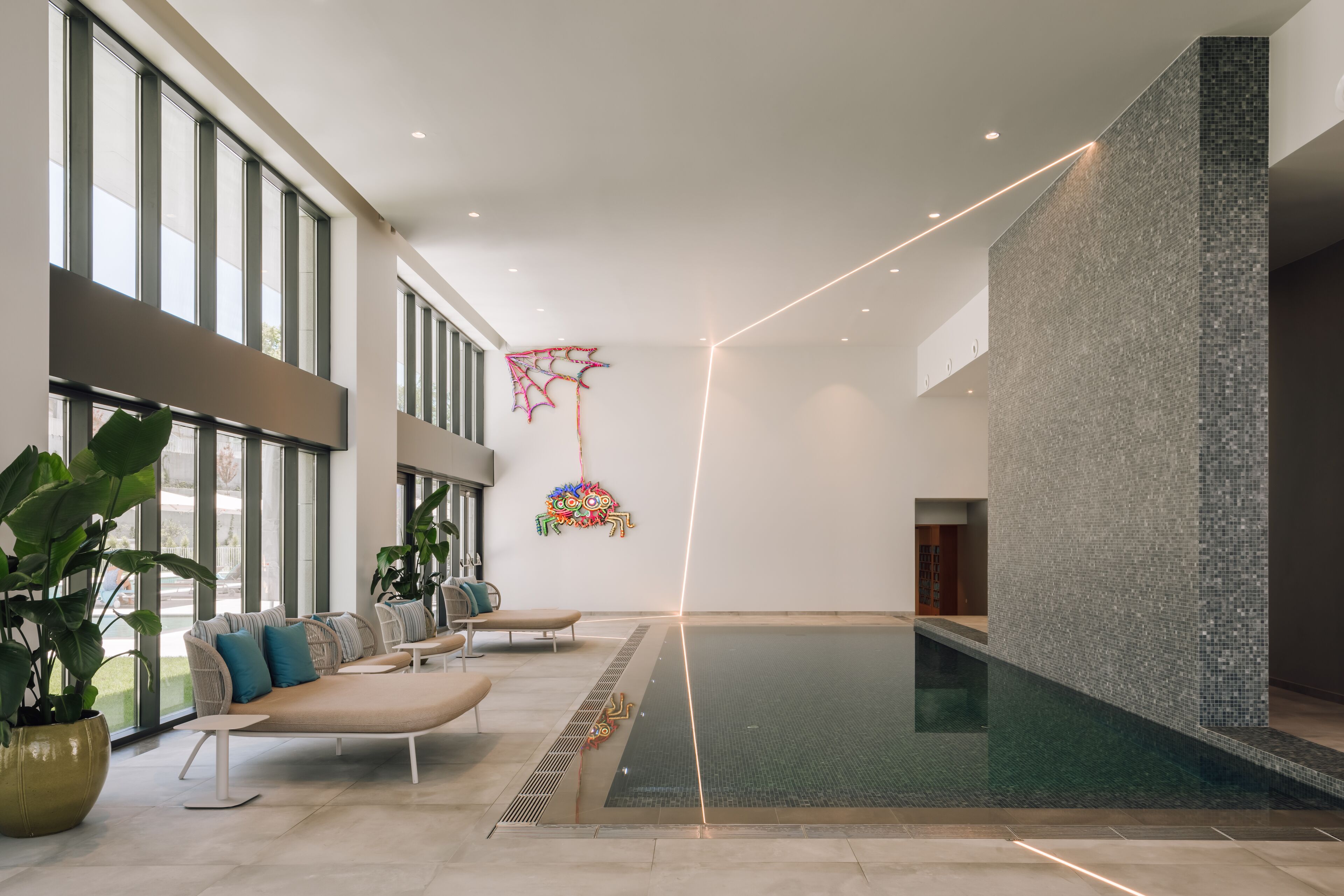 Un área interior de piscina amplia con vista despejada, asientos y una pared decorativa.