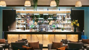 A bar area with multiple shelves of bottles and a seating area with sofas and cushions. - Martinhal Lisbon Oriente (Lisbon)