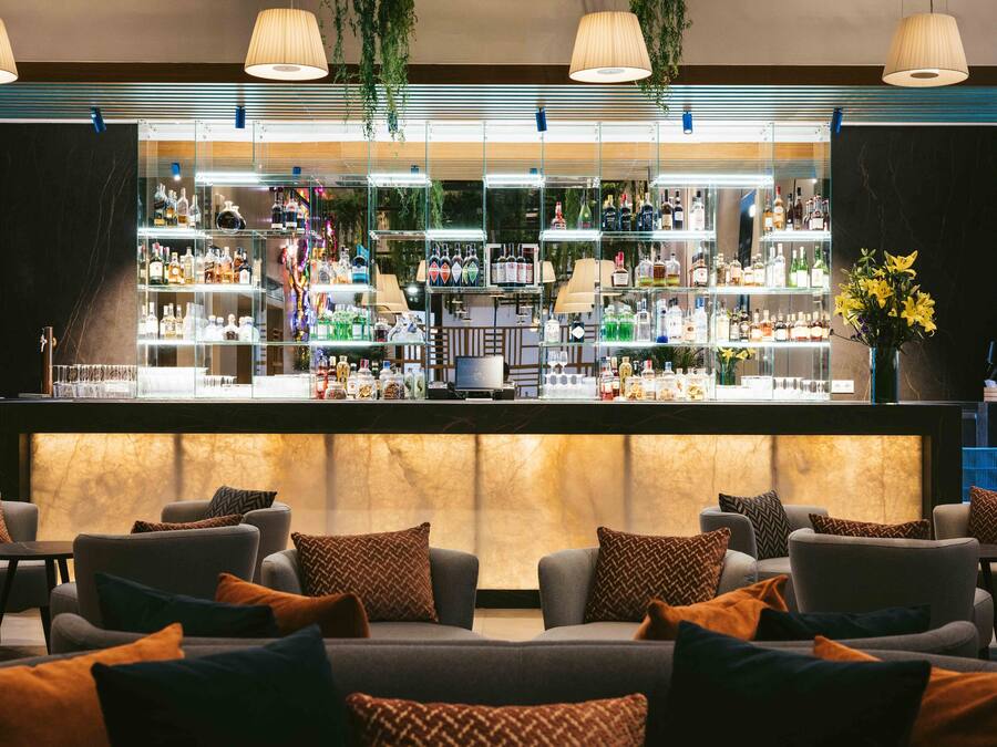 A bar area with multiple shelves of bottles and a seating area with sofas and cushions.