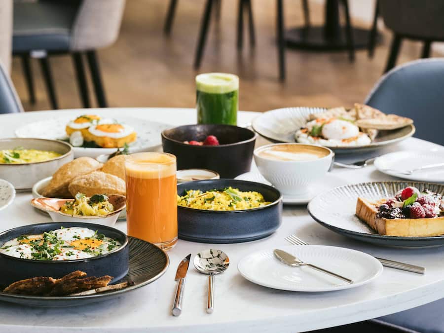 A table set with various dishes, including a bowl of soup, a plate of eggs, and a glass of juice.