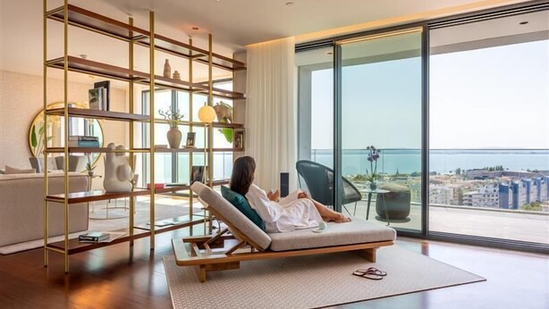 A modern living room with a large window, a sofa, and a decorative shelf. - Martinhal Lisbon Oriente (Lisbon)