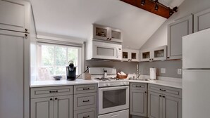 A kitchen with white cabinets, a stove, a microwave, and a window. - Historic headquarters of city founder! Gated parking! (Saint Charles)