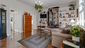 A living room with hardwood floors, a sofa, a coffee table, and a fireplace with a brick wall. - Historic headquarters of city founder! Gated parking! (Saint Charles)