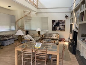 A cozy living room with a staircase, a fireplace, and a bookshelf.