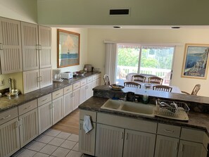 A kitchen with a dining area, featuring cabinets, a sink, and a window with a view.