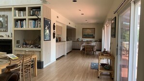 Eine geräumige Küche mit Holzausstattung, ein Essbereich mit Tisch und Stühlen sowie ein großes Fenster für natürliches Licht.