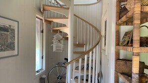 Eine Wendeltreppe mit weißen Geländern und Holzstufen, die zu einer zweiten Etage führt.
