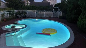 Ein Pool mit geschwungenem Design, eine kleine runde Whirlwanne und eine Zitronenscheibe als Dekoration.
