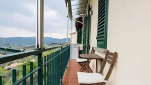 A balcony with a view of distant mountains, a wooden bench, and a table. - Fiesole is Magic (Fiesole)