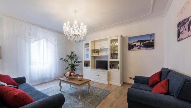 A living room with two sofas, a coffee table, and a chandelier. There is a bookshelf and a painting on the wall. - Fiesole is Magic (Fiesole)