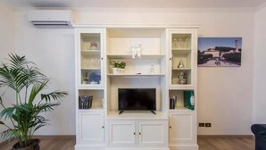 A living room with a white entertainment unit, a flat-screen TV, and a potted plant. - Fiesole is Magic (Fiesole)