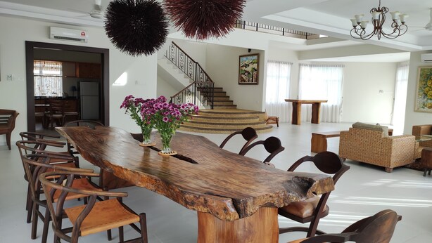 Amplia sala de estar con una mesa de comedor de madera, sillas, una escalera y un sofá.